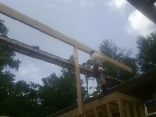 Carpenter setting a ridge beam over a new addition frame — Ice Dam Removal by Roofing Brothers in Pownal