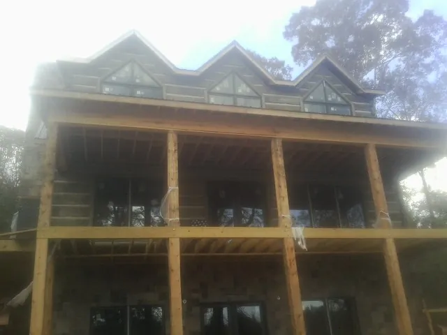 Dormers and porch framing on a large log home under construction — Roof Coating work by our crew in Pownal