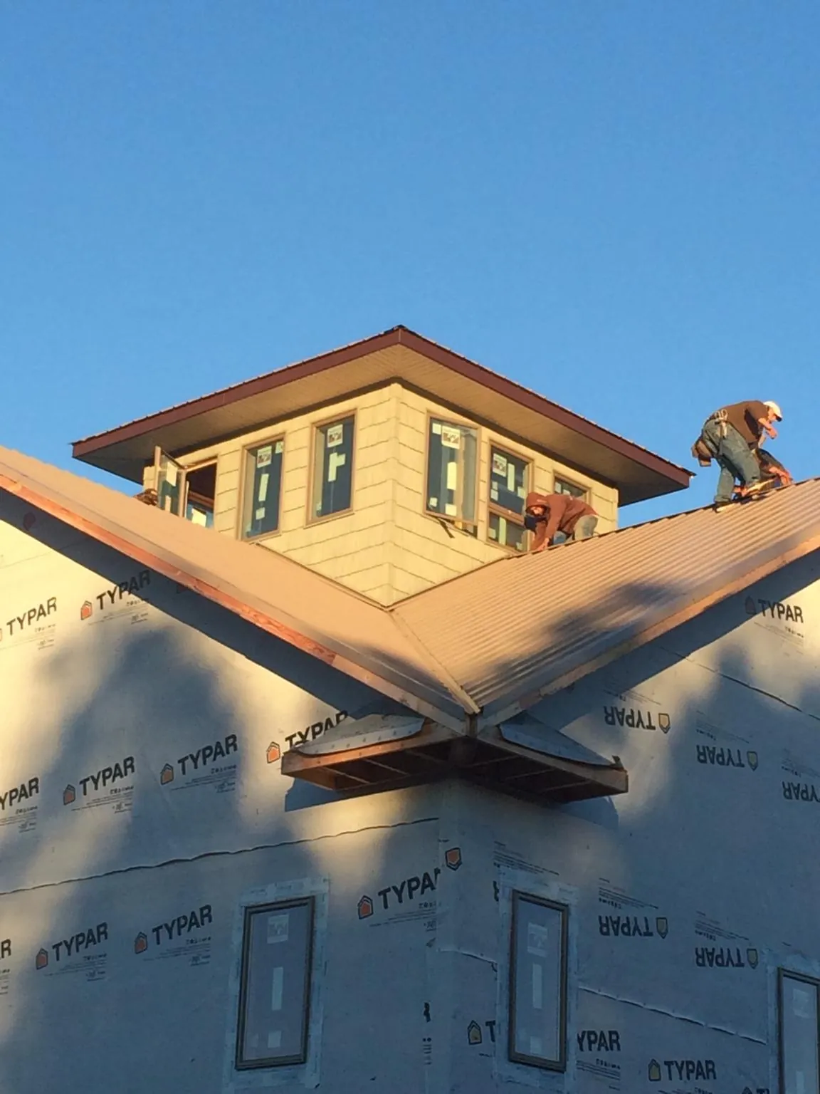 Roofers working around a rooftop cupola on a new metal roof at sunset — Roof Waterproofing in Pownal by Roofing Brothers